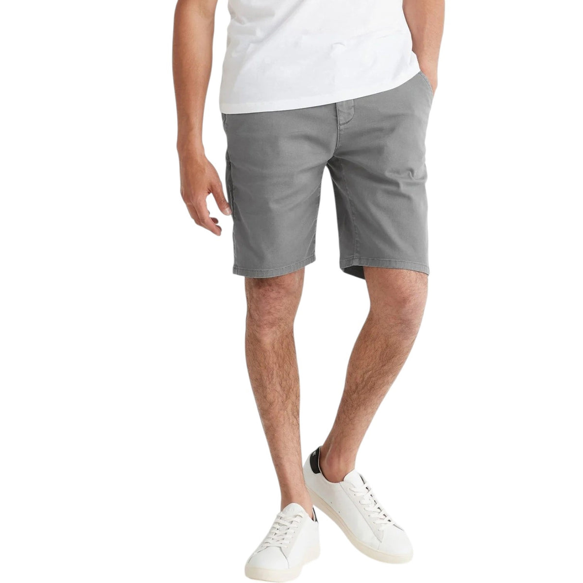 A person faces away from the camera, wearing a white T-shirt, DUER Live Free Journey Shorts in Titanium (slim fit), and white sneakers with black heel tabs, set against a plain white background.
