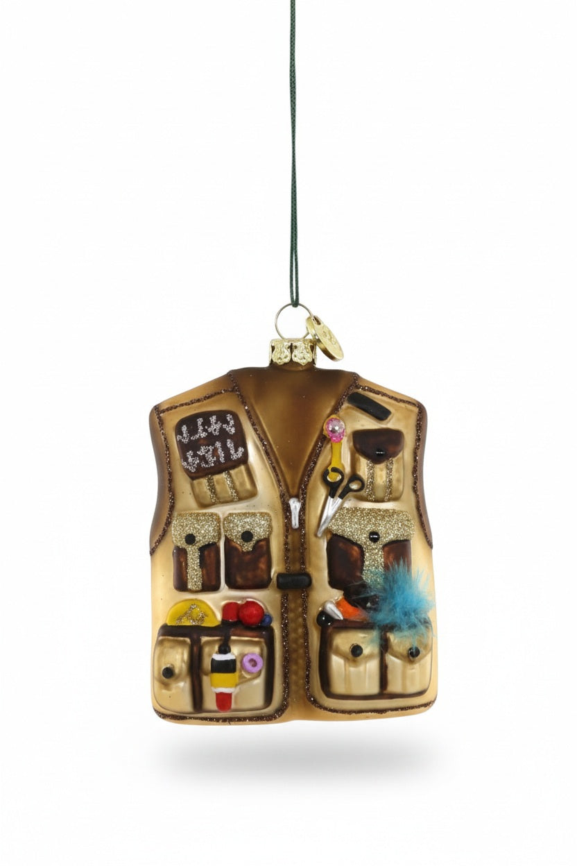A 3-inch GLASS FLY FISHERMAN’S VEST ORNAMENT shaped like a tan vest, complete with multiple pockets, tools, and fishing gear attached.