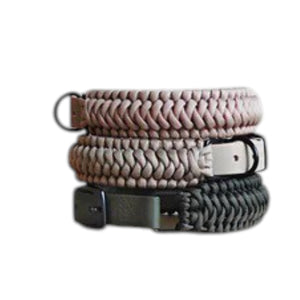 Two LAMBWOLF COLLECTIVE NEW JUPITER Dog Collars in small, one in beige and one in gray, are stacked on a light wooden surface against a plain, light-colored wall. Designed by LAMBWOLF COLLECTIVE, each collar combines cushioned comfort with sturdy durability, making them perfect for everyday wear.