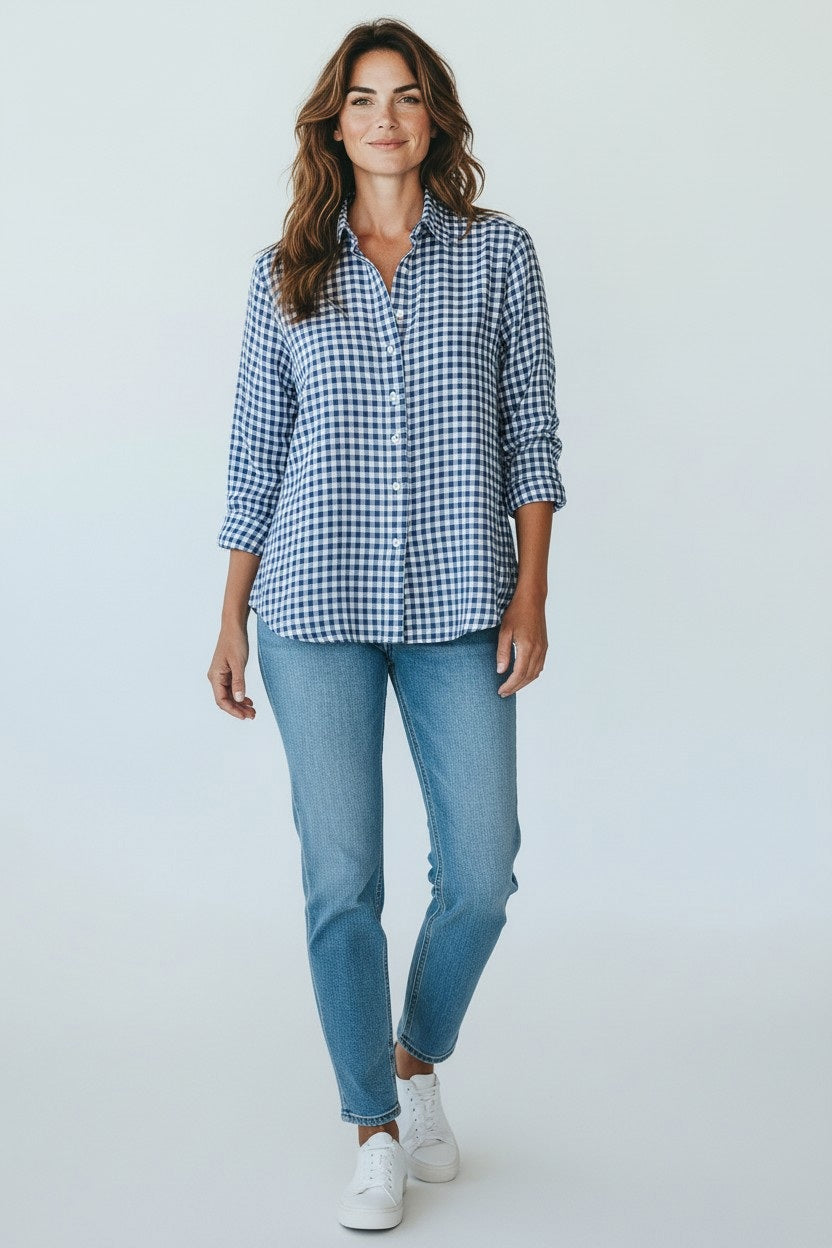A woman smiles in the FRANK &amp; EILEEN EILEEN Relaxed Button Up in Italian Classic Linen Blue Check, paired with light blue jeans and white sneakers, set against a plain light background.