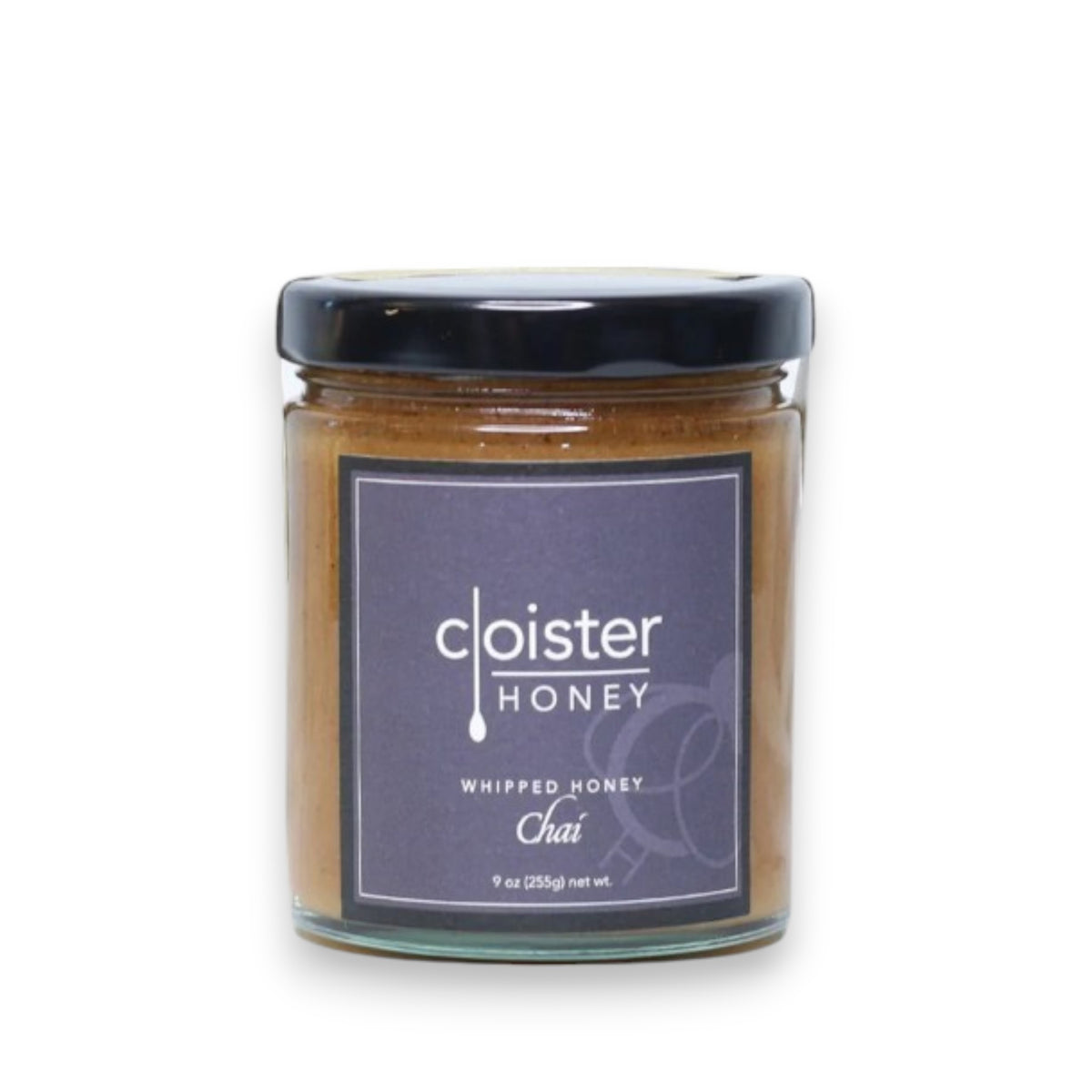 A 9oz jar of Cloister Honey's Whipped Chai Honey features a black lid and a label with "Cloister Honey" and "Whipped Honey Chai" in white text. The light brown, creamy honey inside is infused with fragrant spices for a delightful taste.