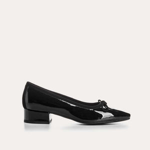 The REQINS FETICHE heeled ballerina shoe features black patent leather, a rounded toe, small bow detail, and a block heel, shown on a plain white background.