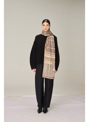 Illustration of a grand building with arched windows, surrounded by flying open books against a brown background. The structure evokes a library or theater, depicted in detailed, architectural style—perfectly suited as inspiration for the INOUI EDITIONS - VIVIENNE WOOL SCARF IN BROWN by INOUI.