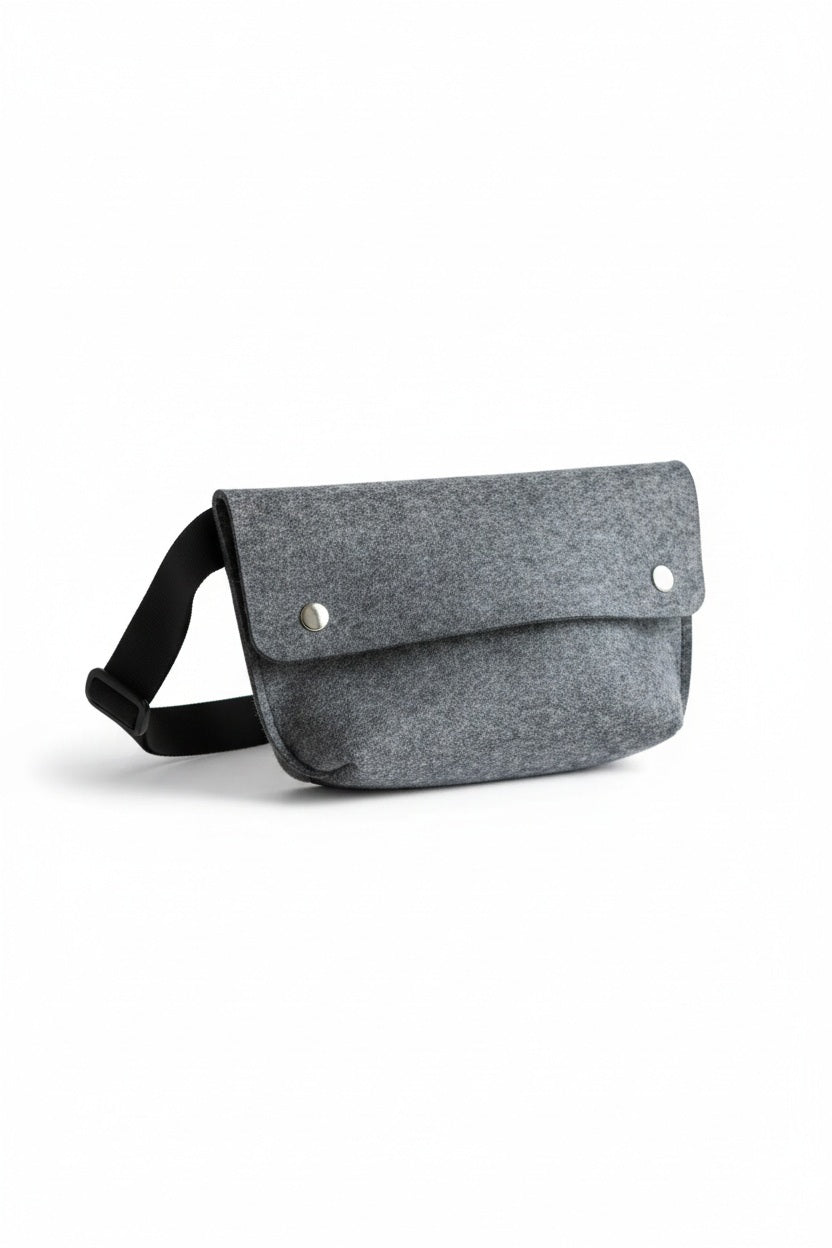 The WOOLBERRY - FELTED WOOL BELT BAG by WOOLBERRY is a small green belt bag crafted from felted wool, featuring a flap secured by two silver snap buttons, and is displayed against a white background.