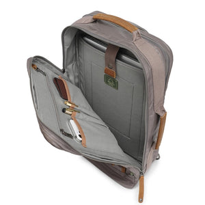 A close-up of the TSD BRAND - MADRONE Coated Canvas Backpack in Grey shows its brown leather accents and an unzipped front pocket with a black wallet partially visible inside.