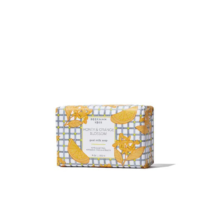 A BEEKMAN - STA ELEMENTS HONEY &amp; ORANGE BLOSSOM 3.5 SOAP bar wrapped in decorative paper featuring orange slices and flowers on a gray and white checkered background.