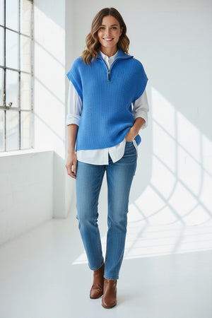 A woman with straight brown hair wears the HINSON WU - BROOKE SLEEVELESS KNIT VEST, a bright blue textured cotton-silk sweater, over a white shirt and blue jeans, standing against a plain light background.