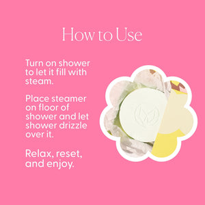 A blue box labeled “MUSEE - WATER LILY & LINEN SHOWER STEAMERS” from MUSEE sits behind five round white tablets, each embossed with a delicate leaf design. These shower steamers offer a spa-like escape, infused with the gentle scent of water lily. Above the text on the box, a small showerhead icon is featured.