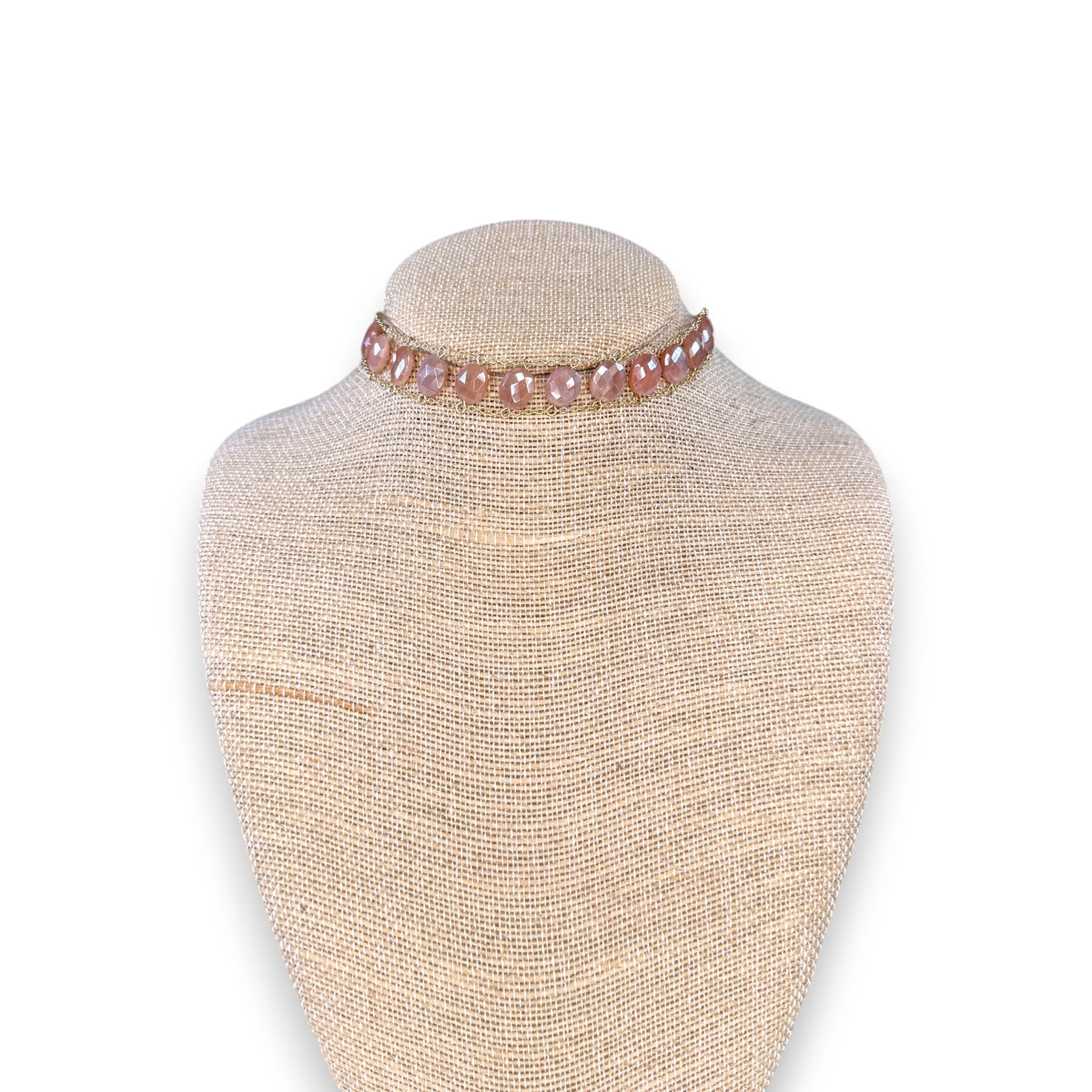 A close-up of a woman&#39;s neck wearing the GOLDISH Ladders to Bliss Pink Moonstone Choker, featuring two rows of round moonstones set in gold-toned chain links, by GOLDISH, against a neutral background.
