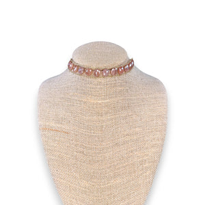 A close-up of a woman's neck wearing the GOLDISH Ladders to Bliss Pink Moonstone Choker, featuring two rows of round moonstones set in gold-toned chain links, by GOLDISH, against a neutral background.