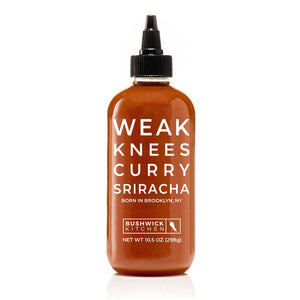 A 10.5 oz (298g) bottle of Bushwick Kitchen's 'Weak Knees' Curry Sriracha sauce, featuring a black cap and a white label prominently displaying "WEAK KNEES CURRY SRIRACHA BORN IN BROOKLYN, NY" in large bold letters, offers a unique twist on classic sriracha with its curry flavor.