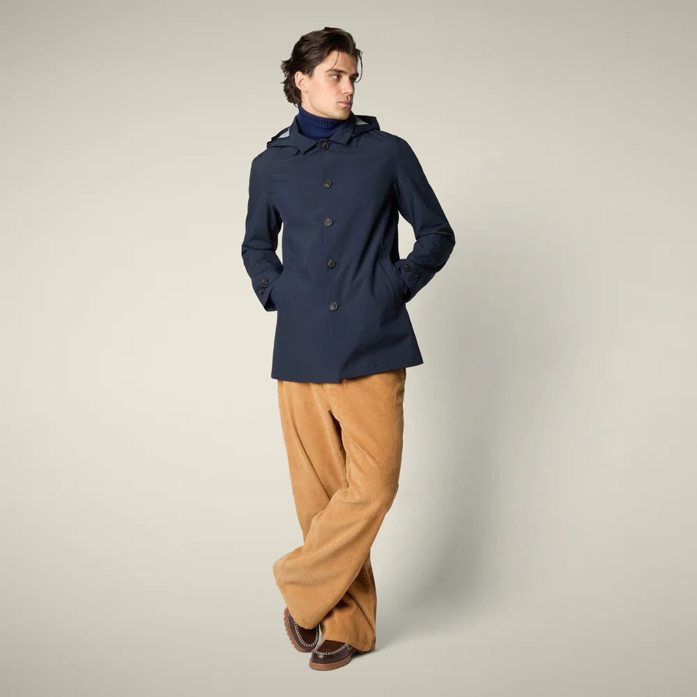 The SAVE THE DUCK - BENJAMIN Hooded Raincoat in Blue Black is a men's lightweight waterproof jacket made from recycled polyester, featuring a button-down front and classic design. Displayed on a plain light beige background.