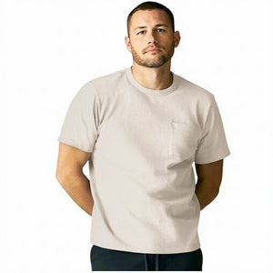 A man with short hair and a beard wears the MACK WELDON Heavyweight Slub Cotton Pocket T-Shirt in Froth, standing against a plain white background with his hands behind his back, looking at the camera.
