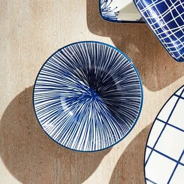 The NAPA HOME AND GARDEN - BLUE AND WHITE STRIA BOWL features a smooth blue exterior and an interior lined with thin vertical blue and white stripes for a modern look.