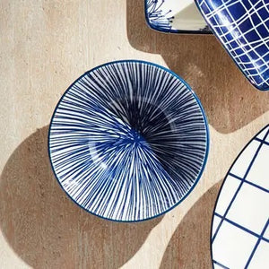 The NAPA HOME AND GARDEN - BLUE AND WHITE STRIA BOWL features a smooth blue exterior and an interior lined with thin vertical blue and white stripes for a modern look.