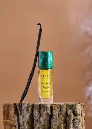 A yellow bottle of LAFCO - FINE FRAGRANCE, FIRESIDE LIGHT 10ML stands upright on a white background, featuring a marble-patterned green cap and reflecting the ambered vanilla notes of this vegan perfume.