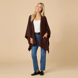 A woman wearing a black SOFTIES - SOLID RIB MARSHMALLOW SHAWL over a grey top and white trousers.