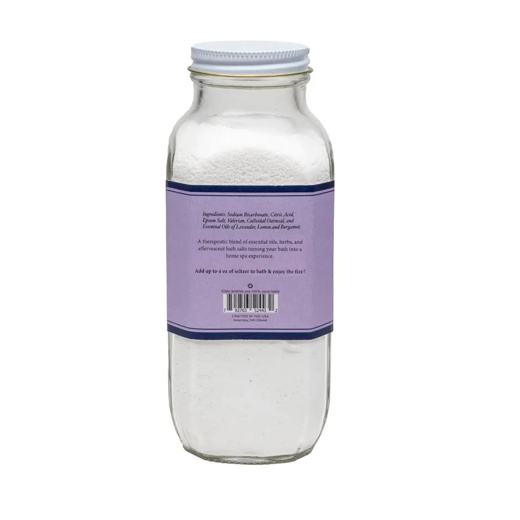 A clear glass jar with a purple label reveals &quot;BAUDELAIRE - SLEEP BATH SELTZER.&quot; The 18 oz of white powder inside offers a handmade, therapeutic experience with its effervescent formula and natural essential oils.