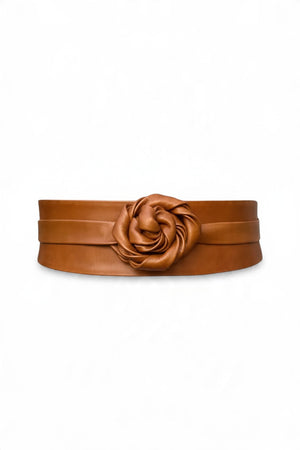 ADA - LEATHER WRAP BELT IN TOFFEE, a tan leather belt featuring a large rose-shaped accent at the center, worn over a cream-colored dress as a versatile one-size accessory.