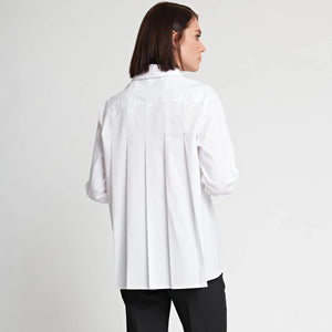 A person with medium-length dark hair wearing the HINSON WU SARA Long Sleeve Pleated Back Shirt, featuring a shirt collar and long sleeves, paired with black pants, stands against a plain white background. They have one hand in their pocket and are gazing slightly to the side, giving a relaxed and contemplative expression.