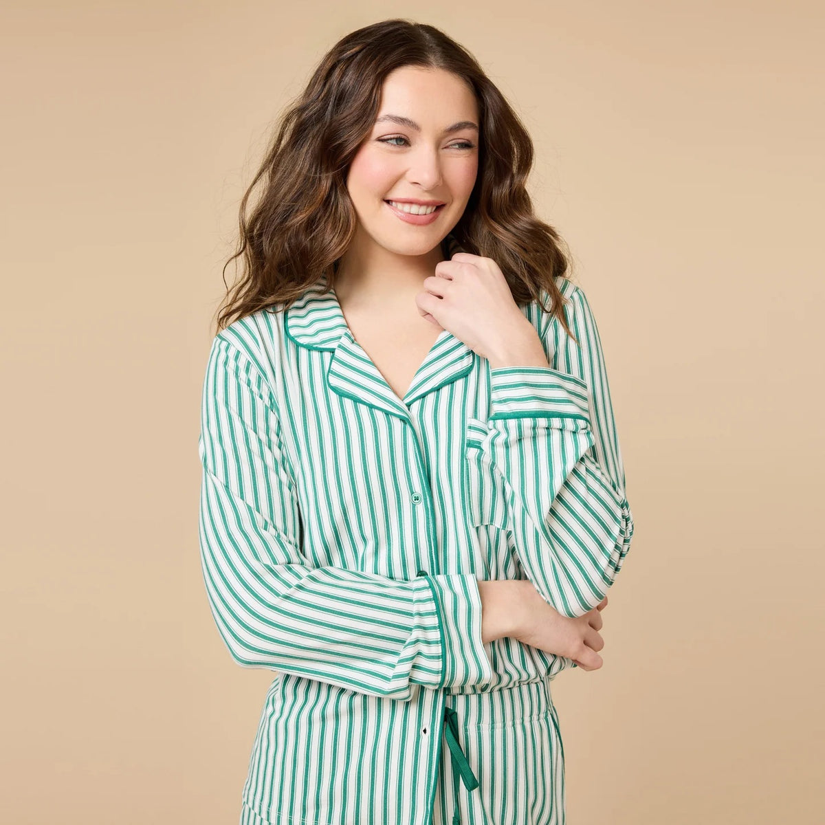 A woman wears the SOFTIES ARIA SLIM NOTCH COLLAR PJ SET, featuring a long-sleeved button-down top and matching wide-leg pants in red and white vertical stripes with red piping details.
