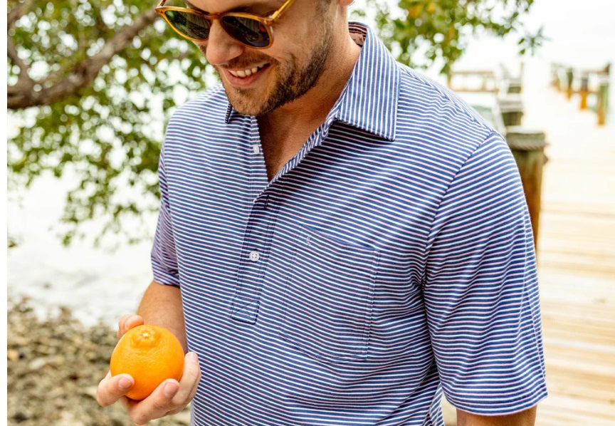 Close-up of a person wearing the CRIQUET Top-Shelf Players Shirt in Stewart Stripe Navy, featuring blue and white stripes, a collar, three buttons, and a small chest pocket. The face is not visible.