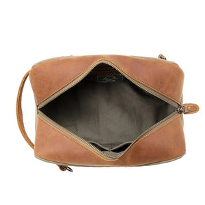 The TSD BRAND Valley Oak Toiletry Bag in olive is a rectangular, handcrafted travel essential made from durable canvas, featuring a tan leather strap and a small leather patch for added style.