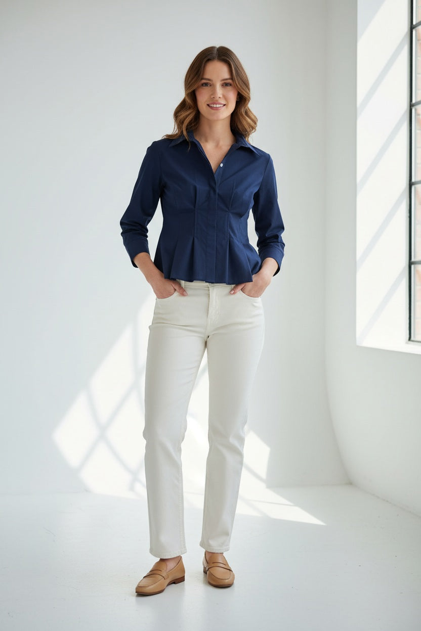 A woman with long red hair wears the HINSON WU - MARTINA 3/4 SLEEVE STRETCH POLISHED COTTON SHIRT IN NAVY, paired with white pants, standing against a plain light background.