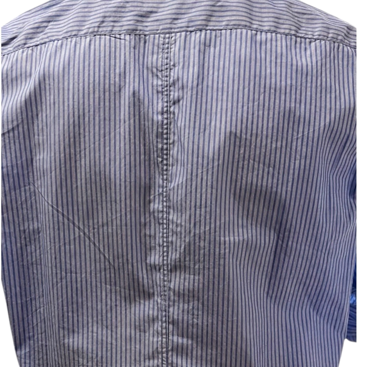 A man in a FRANK &amp; EILEEN Finbar Men's Button Up Shirt in Blue Stripes, blue jeans, and white sneakers walks confidently down a sunny, tree-lined cobblestone street.