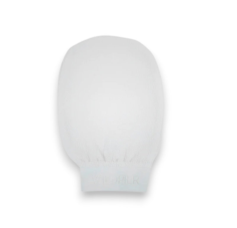 The WILDPIER DEEP EXFOLIATING GLOVE is white with a slightly rounded top and elastic wristband, designed to reveal radiant skin. It's shown against a plain white background.