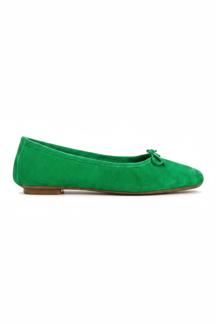 Top view of the REQINS - HARMONY suede ballerina flat in Gazon Green, featuring a small bow on the toe, photographed on a plain light background.