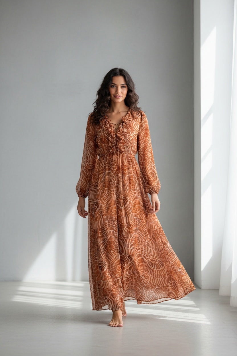 The SFIZIO - RUST PRINT RUFFLED DRESS by SFIZIO is a long-sleeved, floor-length Italian dress in airy viscose creponne with a cinched waist, ruffled neckline, and abstract brown/beige print on lightweight, semi-sheer fabric.