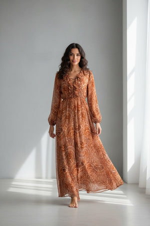 The SFIZIO - RUST PRINT RUFFLED DRESS by SFIZIO is a long-sleeved, floor-length Italian dress in airy viscose creponne with a cinched waist, ruffled neckline, and abstract brown/beige print on lightweight, semi-sheer fabric.