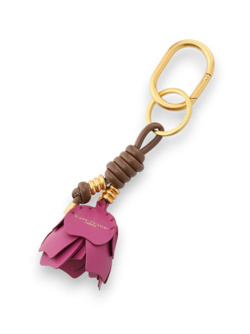The GIANNI CHIARINI Desert Flower Key Ring/Bag Charm features a gold keychain with a purple synthetic leather flower, brown leather and gold bead accents, plus a gold clip and ring.