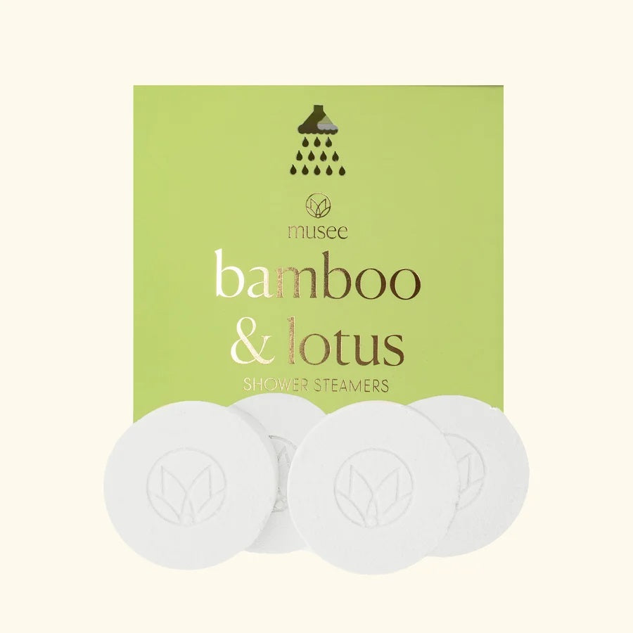 A pink graphic features instructions for using MUSEE - BAMBOO & LOTUS SHOWER STEAMERS, along with an image of a round white tablet displayed in a flower-shaped frame. The text explains how to use this signature natural bath product from MUSEE to create a spa-like, relaxing shower experience.