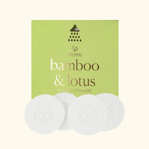 A pink graphic features instructions for using MUSEE - BAMBOO & LOTUS SHOWER STEAMERS, along with an image of a round white tablet displayed in a flower-shaped frame. The text explains how to use this signature natural bath product from MUSEE to create a spa-like, relaxing shower experience.