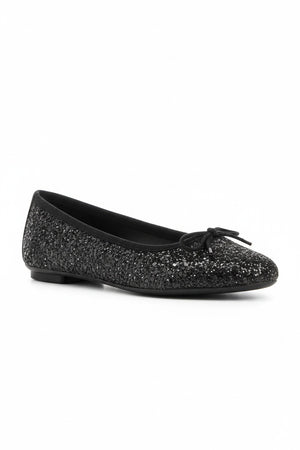 The REQINS Harmony Sequin Ballerina Flats in Noir feature black sequins, black toe caps, and small bows—bringing a touch of everyday luxury against a plain light background.