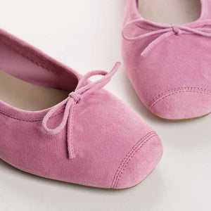 The REQINS - HARMONY SUEDE BALLERINA FLATS IN PINK by REQINS feature soft suede leather, a low heel, simple design, and a small front bow, shown against a plain light background.