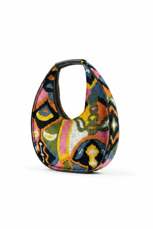 The BALDIZ LUCA Bag in Paloma is a large, crescent-shaped shoulder bag with a black handle and vibrant abstract floral patterns—perfect for everyday use.