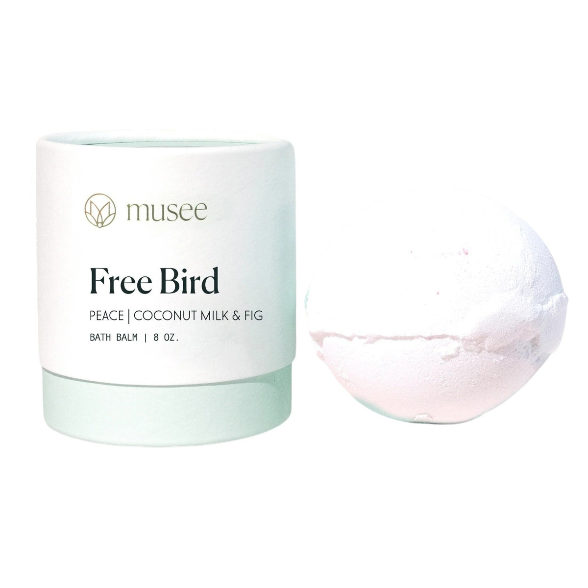 A light green and white container labeled “MUSEE - FREE BIRD THERAPY BATH BALM” sits beside a white bath bomb, offering a soothing and therapeutic bath experience with natural ingredients and coconut essential oil.