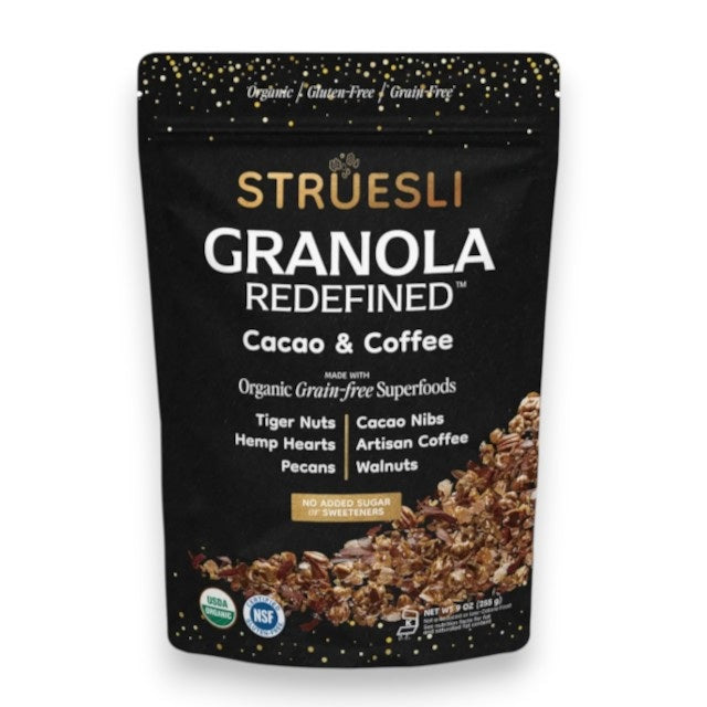 A black and gold pouch labeled "STRUESLI - CACO + COFFE GRANOLA" from STRUESLI showcases its grain-free, unsweetened, prebiotic, plant-based granola made in small batches, set against a plain background.