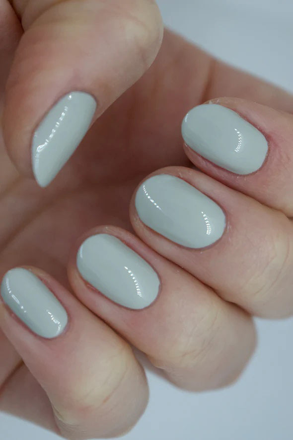 A glass bottle of TENOVERTEN - NAIL POLISH from the brand TEN OVER TEN, featuring a white cap and a dusty pink nail color. The front label displays "TEN OVER TEN" in white uppercase letters. This vegan, eight-free formula ensures both beauty and peace of mind. The background is plain and light-colored.