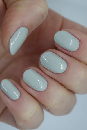 A glass bottle of TENOVERTEN - NAIL POLISH from the brand TEN OVER TEN, featuring a white cap and a dusty pink nail color. The front label displays "TEN OVER TEN" in white uppercase letters. This vegan, eight-free formula ensures both beauty and peace of mind. The background is plain and light-colored.