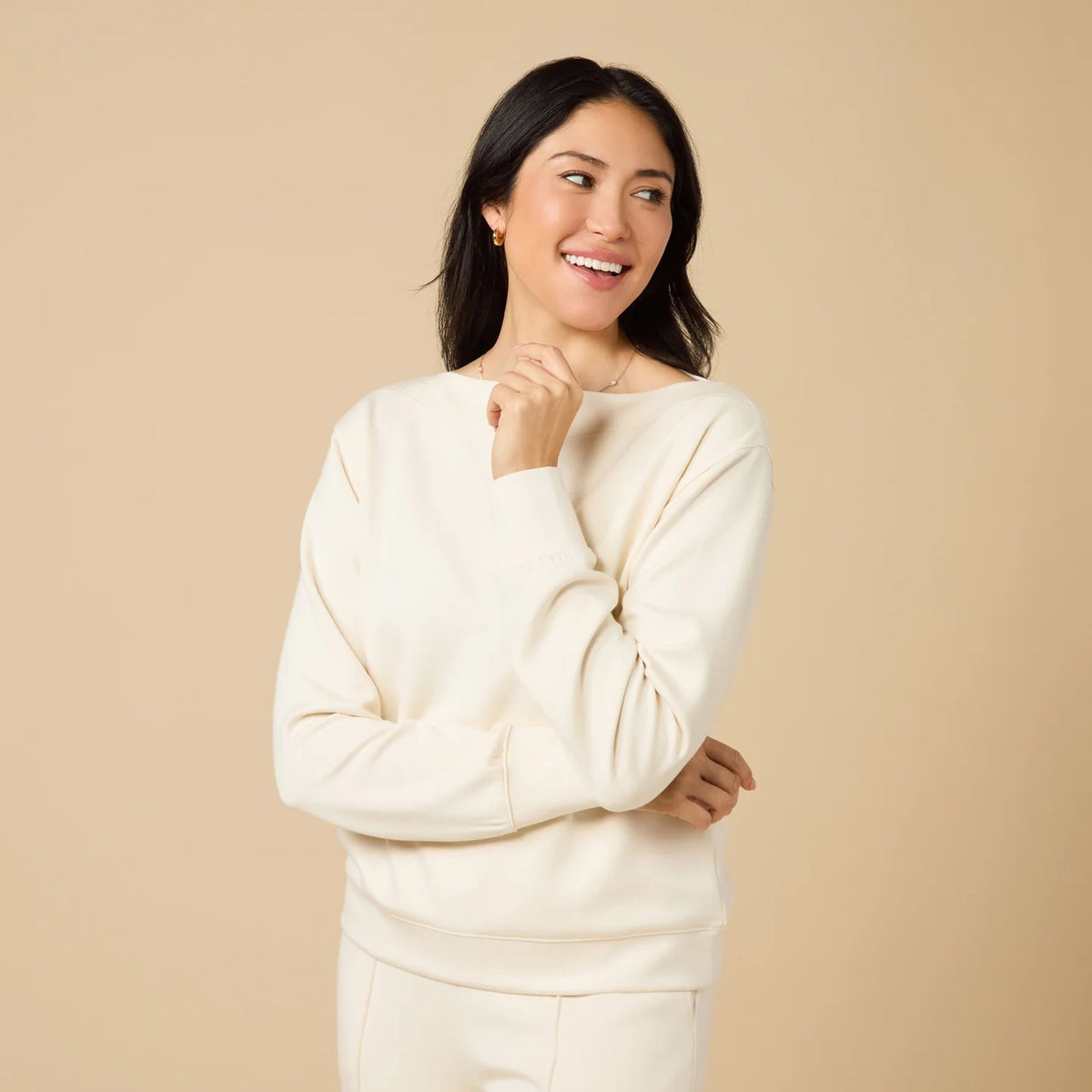 A woman wears a SOFTIES - DREAMTECH BOAT NECK WITH PINTUCK PANT SET in olive green, featuring a long-sleeve boat neck top and matching wide-leg pintuck pants.