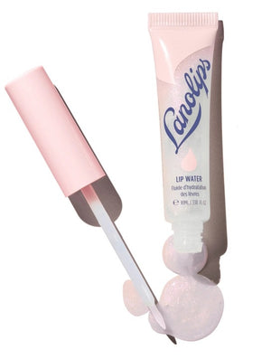 A close-up of a person smiling with glossy pink lips—enhanced by LANOLIPS - LIQUID LANOLIN LIP WATER from LANOLIPS—and smooth brown skin against a light blue background.