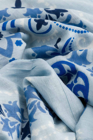 Crafted from soft cotton voile for an elegant yet lightweight feel, the MAISON LECOMTE - BANDANA DINARD SARONG by MAISON LECOMTE FLAMENT features a rectangular silhouette in light blue and white. Detailed with intricate blue floral and paisley patterns and decorative borders reminiscent of a traditional Persian rug, this piece is both stylish and comfortable.