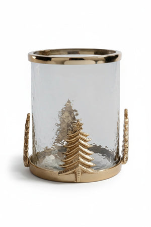 ZODAX GLASS AND ALLOY HURRICAN IN GOLD featuring a clear cylindrical glass and steel hurricane lamp with a gold-toned base, rim, and decorative gold Christmas tree embellishments on the sides.