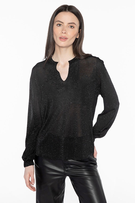 A person with long dark hair, wearing the KINROSS CASHMERE - SHIMMER SPLITNECK TOP and black leather pants, stands against a plain white background. The top shimmers subtly, hinting at the delicate interplay of Viscose and Metallised Fiber woven through it.