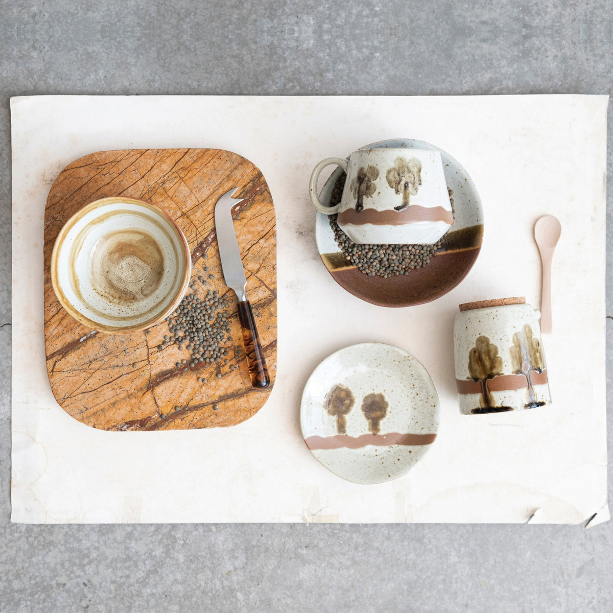 The STONEWARE LOW BOWL IN EARTH TONE REACTIVE GLAZE by CREATIVE COOP features a speckled off-white top, solid brown bottom, and an olive-brown stripe, highlighting handcrafted artistry with a beautiful reactive glaze finish.