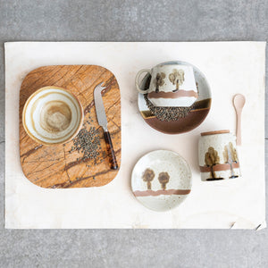 The STONEWARE LOW BOWL IN EARTH TONE REACTIVE GLAZE by CREATIVE COOP features a speckled off-white top, solid brown bottom, and an olive-brown stripe, highlighting handcrafted artistry with a beautiful reactive glaze finish.